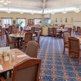 Spacious dining room with neatly arranged tables and chairs, featuring a patterned carpet and soft lighting.