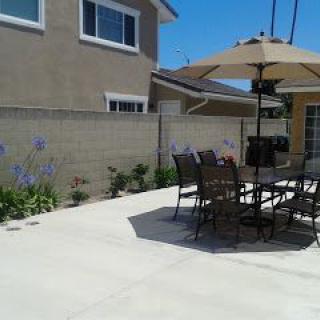 A sunny backyard patio with outdoor furniture and an umbrella.