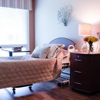 A serene hospital room with a neatly made patient bed, warm lighting, and a touch of nature.