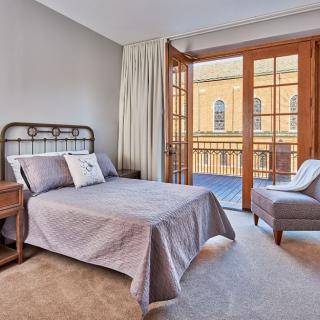 A cozy bedroom with a bed, chair, and balcony access.