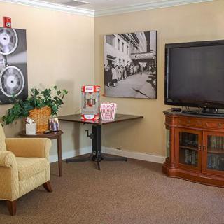 A cozy living room featuring a TV, armchair, and popcorn machine.