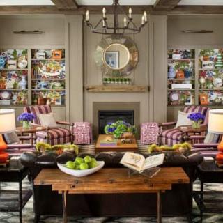 A vibrant living room featuring colorful decor, a central fireplace, and stylish furniture.