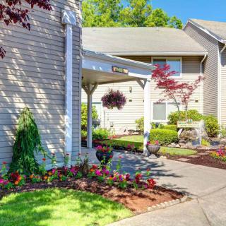 A well-maintained apartment complex with beautiful landscaping and colorful flowers in a sunny setting.