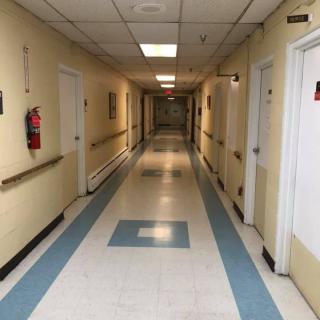 A long hospital corridor with doors on both sides.