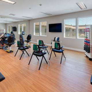 A spacious gym studio equipped with exercise chairs and weights for fitness activities.