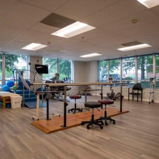 A spacious physical therapy room equipped with rehabilitation equipment and exercise tools.