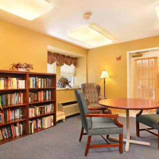 A cozy reading room with bookshelves, a table, and chairs.