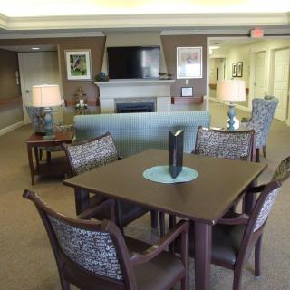 A comfortable lounge area with a table, chairs, lamps, and a television.