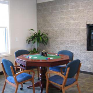 A poker table with chairs in a brightly lit game room.