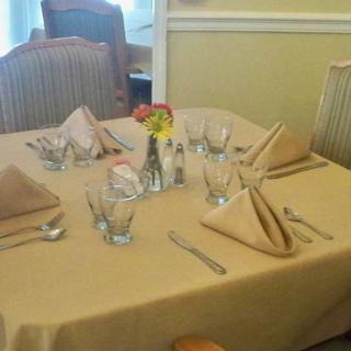 A neatly set dining table with napkins, glasses, and utensils.