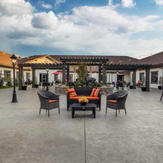 A spacious outdoor patio with comfortable seating and a pergola under a partly cloudy sky.