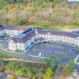 Aerial view of a large building complex with a parking lot surrounded by trees in autumn.