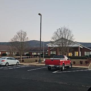A peaceful evening view of a building surrounded by parked vehicles and distant mountains.