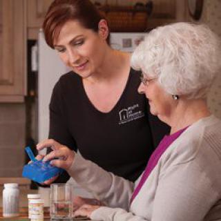 A caregiver assists an elderly woman with her medication.