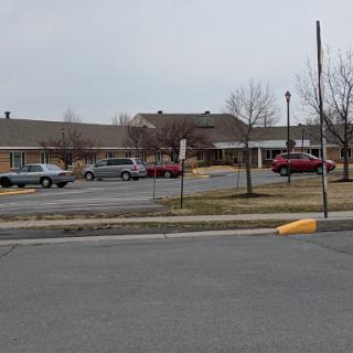 A view of a building with a parking lot and cars on an overcast day.