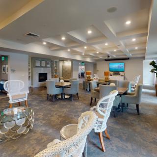 A modern living room with multiple seating areas, stylish furniture, and a television mounted on the wall.