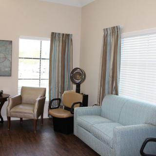 A cozy living room with a sofa, chairs, and large windows.