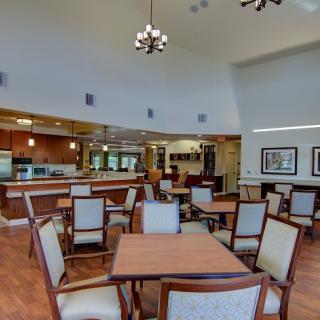 A spacious dining area with neatly arranged tables and chairs, featuring elegant lighting fixtures.