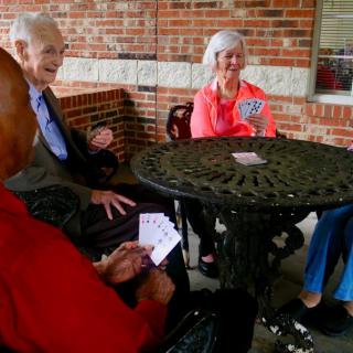 A group of seniors enjoying a card game outdoors.