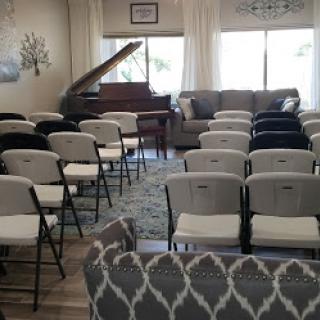 A cozy interior space set up with chairs for an event, featuring a piano in the corner.
