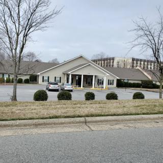 A serene view of a building surrounded by trees and shrubs on a cloudy day.