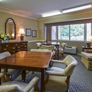 A cozy living room with dining tables and chairs, featuring a large window and elegant decor.