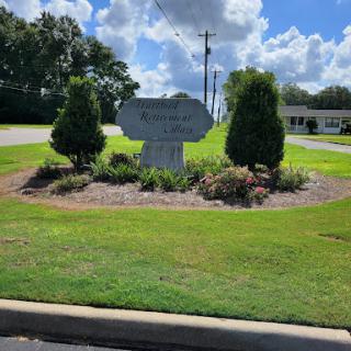 A welcoming sign surrounded by lush landscaping under a clear sky.