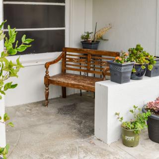 A cozy outdoor patio with a wooden bench and decorative plant pots.