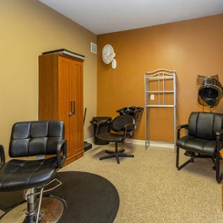 A cozy hair salon space featuring black chairs and warm wall colors.