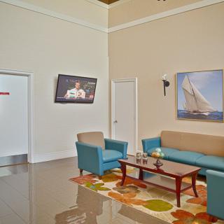 A modern waiting room with comfortable seating, featuring a television and nautical-themed artwork.