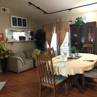 Cozy dining area with a wooden table and chairs, decorated with plants and curtains.