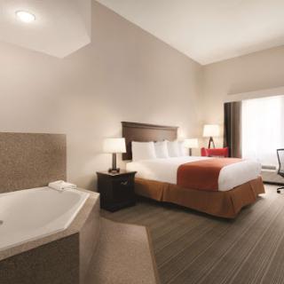 A cozy and modern hotel room featuring a comfortable bed and a relaxing jacuzzi.