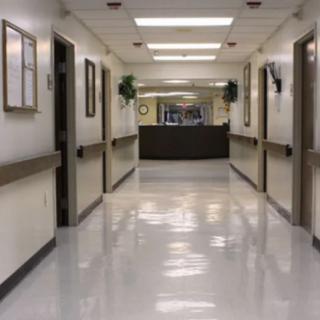 A quiet hospital hallway with clean, shiny floors and fluorescent lighting.