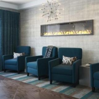 A modern living room with teal chairs and a sleek fireplace.