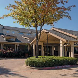 A building entrance with a tree and landscaped area in front.