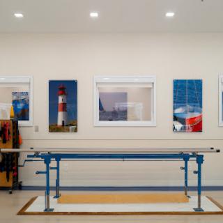 A well-lit workshop featuring a blue work table and decorative photographs of lighthouses on the walls.