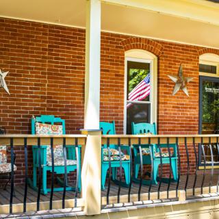 A charming front porch with turquoise chairs and decorative elements against a brick wall.