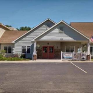 A view of a small building with a sloped roof and driveway, featuring an inviting entrance.