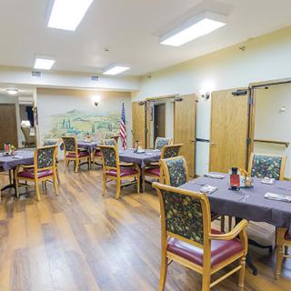 An indoor dining area with multiple tables and chairs arranged neatly on a wood floor.