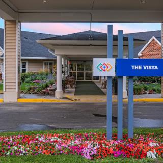 Entrance to a building with well-maintained landscaping and a sign reading 'The Vista'.