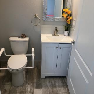 A small, modern bathroom with a toilet and sink, featuring decorative flowers and a mirror.