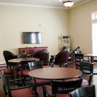 A lounge area with several round tables and chairs, featuring a wall-mounted television.