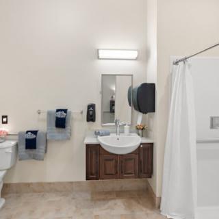 A clean and organized bathroom with a sink, mirror, and shower area.