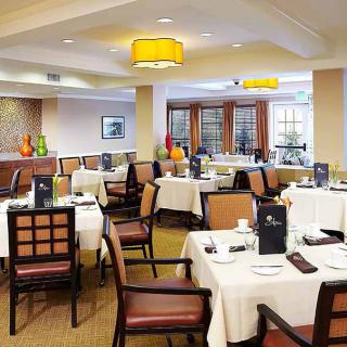 A well-appointed restaurant dining area with neatly arranged tables and chairs, featuring elegant decor and warm lighting.