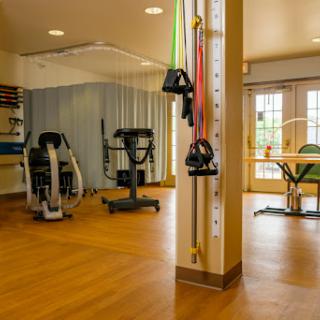 A bright and spacious rehabilitation area equipped with various exercise machines and therapy tools.