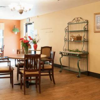 A cozy dining area with wooden tables and chairs, featuring a decorative metal shelf and a light fixture overhead.