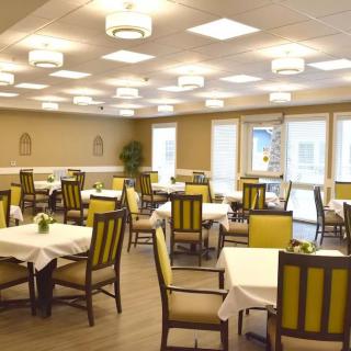 A spacious dining area with neatly arranged tables and chairs under modern lighting.