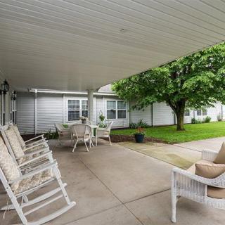 A peaceful patio with rocking chairs and a covered seating area overlooking a garden.