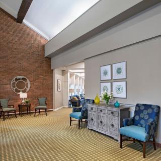 A welcoming lobby area featuring comfortable chairs, a sideboard adorned with decorative items, and artwork on the walls.