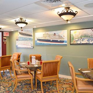 A cozy restaurant interior featuring wooden tables and chairs, decorated with nautical-themed artwork on the walls.